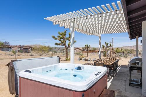 a hot tub on a patio with an umbrella at Horseshoe House - Hot Tub, BBQ and Fire Pit! home in Joshua Tree