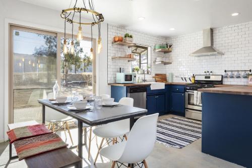 a kitchen with blue cabinets and a table with white chairs at Cosmic Rabbit - Family fun with hot tub!! home in Joshua Tree