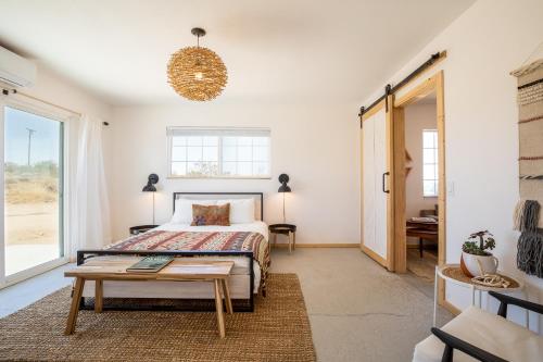a bedroom with a bed and a table at Flamingo Ranch - Dreamy Desert Design with Hot Tub home in Pioneertown