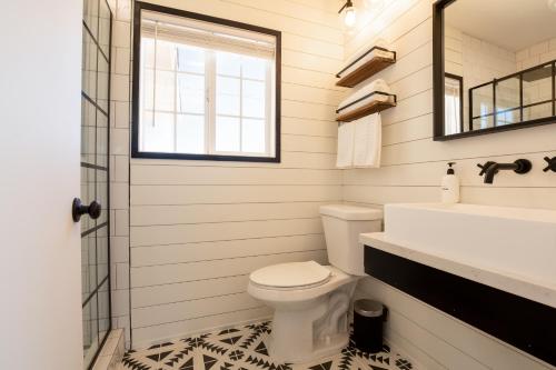 a bathroom with a toilet and a sink and a mirror at Flamingo Ranch - Dreamy Desert Design with Hot Tub home in Pioneertown