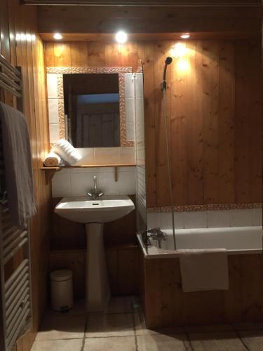 une salle de bain avec un lavabo et une baignoire dans l'établissement Paisible chalet montagne avec option jacuzzi, à Séez