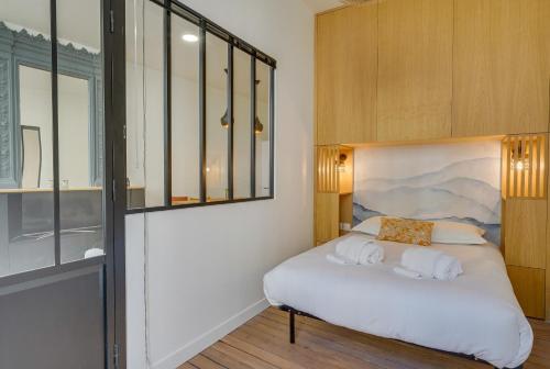 une chambre avec un lit avec des draps blancs et des oreillers dans l'établissement LE 61 - Superbe T2 meublé avec balcon en plein cœur de Bordeaux, à Bordeaux