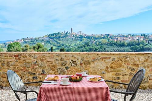 einen Tisch mit einer roten Tischdecke und Stühlen mit Aussicht in der Unterkunft Podere Sant'Elena in San Gimignano