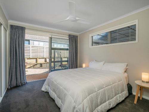 a bedroom with a bed and a large window at Relax on Roseberry - Whitianga Holiday Home in Whitianga