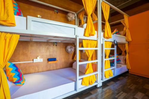 a room with two bunk beds with yellow curtains at goSTOPS Pondicherry Near Auroville in Auroville