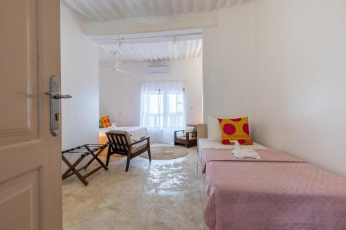 a white room with two beds and a chair at Sharazad Wonders Boutique in Zanzibar City