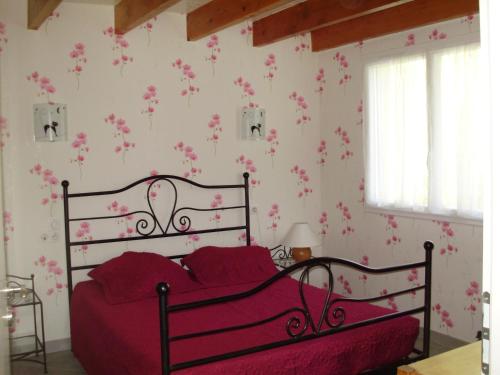 a bedroom with a red bed with pink flowers on the wall at Paradis des Outardes in Beauvoisin