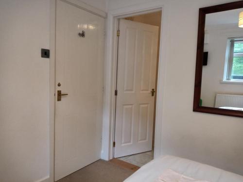a bedroom with a white door and a mirror at West Looe Downs in Looe
