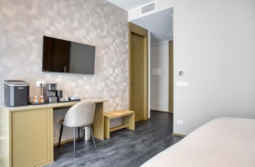 a hotel room with a desk and a tv on a wall at Le Suite del Corso The Smart Boutique Aparthotel By OSPITAMI in Milan