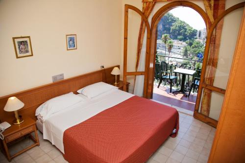 Schlafzimmer mit einem Bett und Blick auf einen Balkon in der Unterkunft Hotel Ipanema in Taormina
