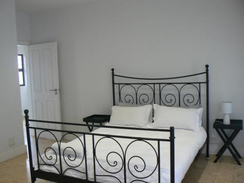 a bedroom with a black bed with white pillows at The Don Lodge in Amanzimtoti