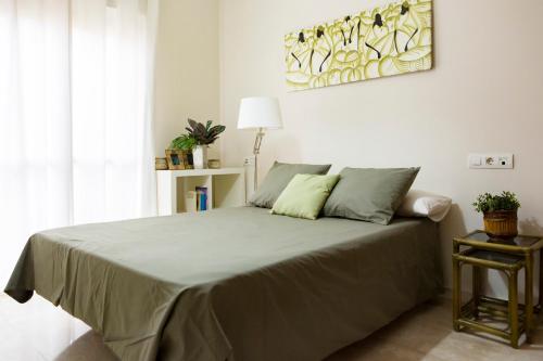 una camera da letto con un grande letto con cuscini verdi di Apartamento Málaga Jalón a Málaga