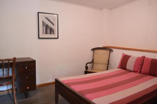 a bedroom with a bed and a dresser and a chair at The Lodge at Galapitiyaya Estate in Haputale