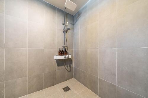 a bathroom with a shower stall with bottles on a shelf at MU Hotel Sasang in Busan