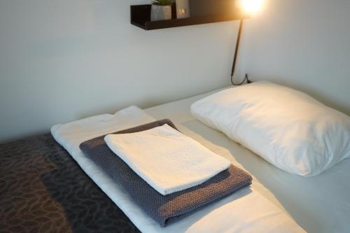 a bed with a pillow and a towel on it at Inn Tourist Hostel in Helsinki