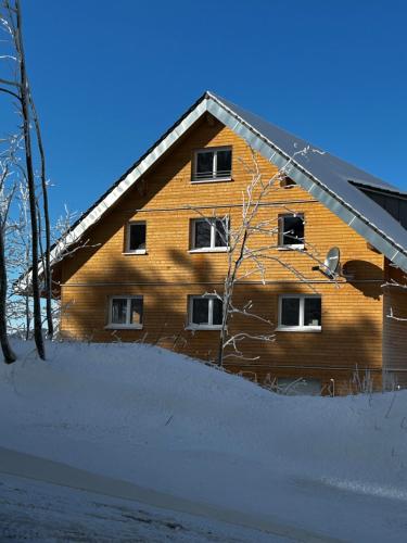 a wooden house with snow in front of it at Feldberg Apartment - direkt an der Skipiste - mit Sauna in Feldberg