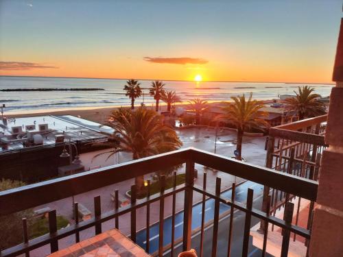 uma vista para a praia ao pôr-do-sol a partir da varanda de um resort em Le Parasol em Porto San Giorgio