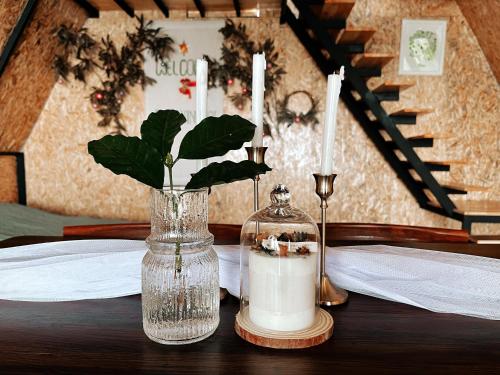 a table with two candles and a vase with flowers at บ้านหิ่งห้อยผาหมี Baanhinghoi phamee in Mae Sai