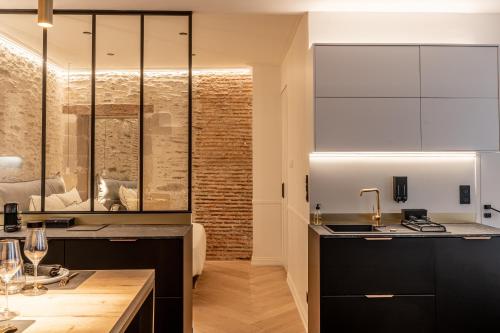 a kitchen with black cabinets and a glass wall at Le Passage Royal - Les Maisons de Madeleine in Nantes