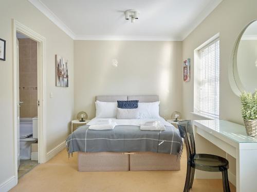 um quarto com uma cama e uma secretária com um espelho em Curb Properties - Gorgeous 3 Bedroom House Close To Town Centre em Cheltenham