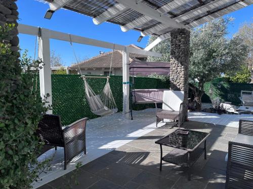 a patio with chairs and a hammock and a house at אלרון - אירוח בגולן in Ani'am