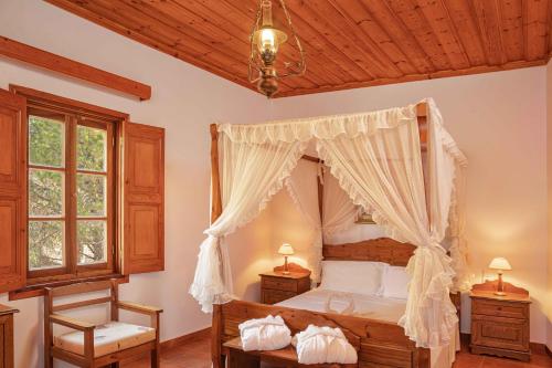 a bedroom with a canopy bed with two tables and two windows at Apolafsis Studios in Patmos