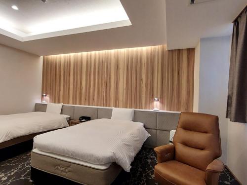 a hotel room with two beds and a chair at The Legato Inn MIFUNE in Mifune