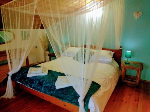 1 dormitorio con cama con dosel y cortinas blancas en Hillside Guesthouse Pushevo en Pushevo