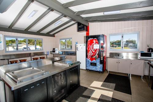 a large kitchen with a cocacola soda machine at Reflections Evans Head - Holiday Park in Evans Head