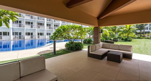 a patio with a couch and a pool and a building at Shore 1 Residences MOA Staycation in Manila