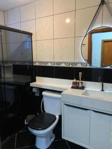 a bathroom with a toilet and a sink and a mirror at Trindade Beach House in Paraty