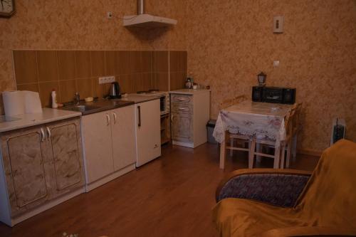een keuken met witte apparatuur en een tafel in een kamer bij KurBrauksim Goldingen Apartments in Kuldīga