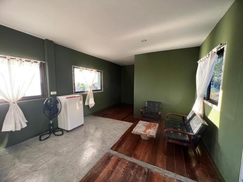 a living room with green walls and a white refrigerator at Char Bungalows in Koh Tao