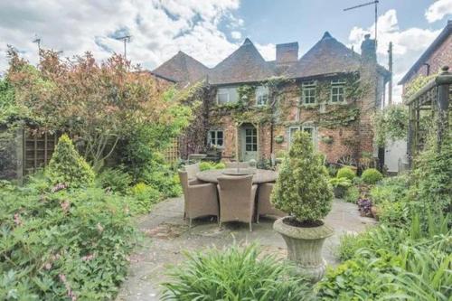 a garden in front of a large brick building at Arms Cottage in Bridge