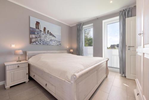 een witte slaapkamer met een groot bed en ramen bij Ferienwohnung Boddenblick in Puddemin