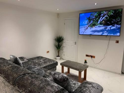 a living room with two couches and a flat screen tv at Lavish The Marble Apartment in Bury Saint Edmunds