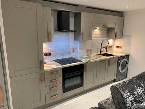 a kitchen with a sink and a stove top oven at Lavish The Marble Apartment in Bury Saint Edmunds