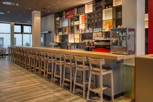 a bar with a row of stools in a restaurant at IntercityHotel Berlin Airport BER Terminal 1 & 2 in Schönefeld