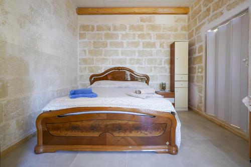 1 dormitorio con cama de madera y pared de ladrillo en La Casa di Marta, en Faccia di Trippa