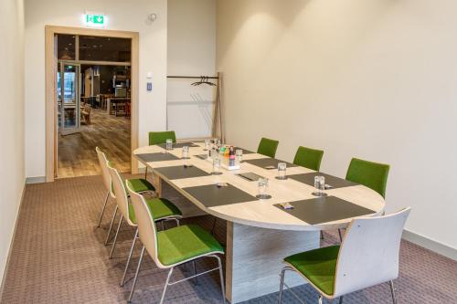 a conference room with a long table and green chairs at IntercityHotel Berlin Airport BER Terminal 1 & 2 in Schönefeld