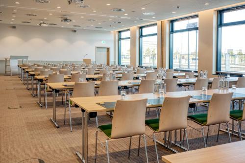 a classroom with tables and chairs in a room with windows at IntercityHotel Berlin Airport BER Terminal 1 & 2 in Schönefeld