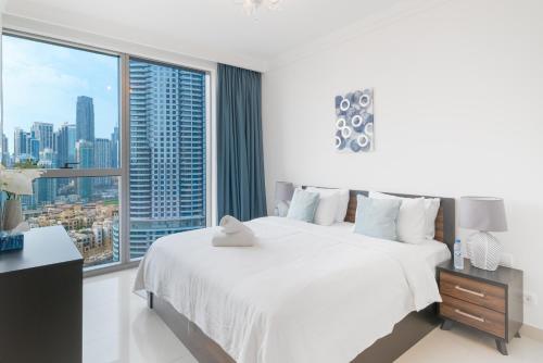 a bedroom with a large white bed and a large window at Holidays R Us Royal View in Dubai