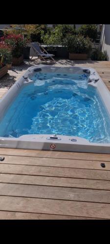 Un grand bain à remous est installé sur une terrasse en bois. dans l'établissement VILLA MADY Adultes Only, à Andernos-les-Bains