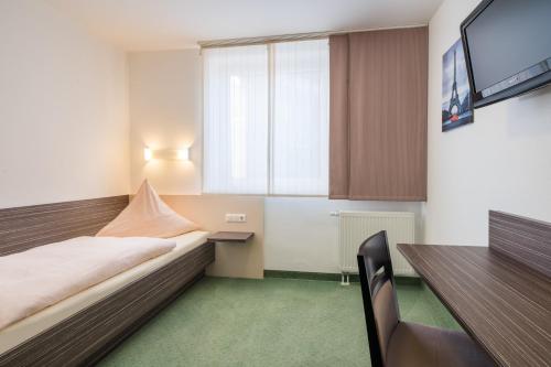 a bedroom with a bed and a desk and a television at Hotel zur Post in Hemmingen