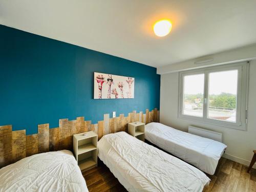 Duas camas num quarto com uma parede azul em Le Miramar, face mer et standing em Saint-Jean-de-Monts