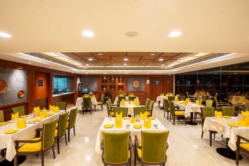 a restaurant with tables and chairs with yellow chairs at Fortune Park Pushpanjali, Durgapur - Member ITC Hotels' Group in Durgāpur