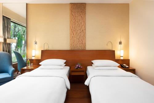 a hotel room with two beds and a blue chair at Hyatt Pune in Pune