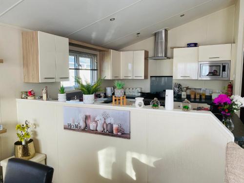 a kitchen with white cabinets and plants on the counter at Highfields Holiday Park Clacton in Clacton-on-Sea