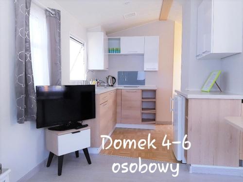 a small white kitchen with a television in it at Azur Domki blisko plaży in Mielno