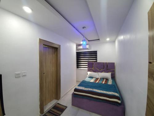 a bedroom with a purple couch in a white room at Dinero Rose-2 Bedroom Apartment in Lagos